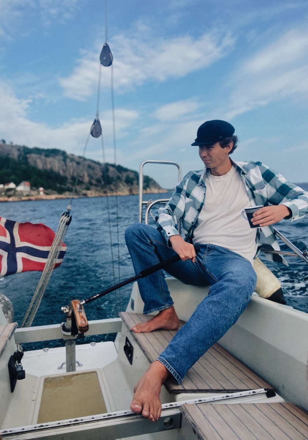 Oskar Solberg at the tiller of a sailboat on the Norwegian coast