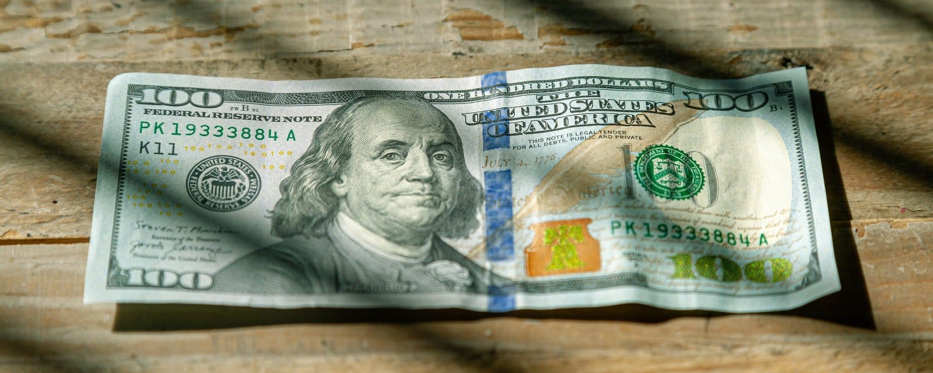 U.S. $100 bill lying on a wooden surface