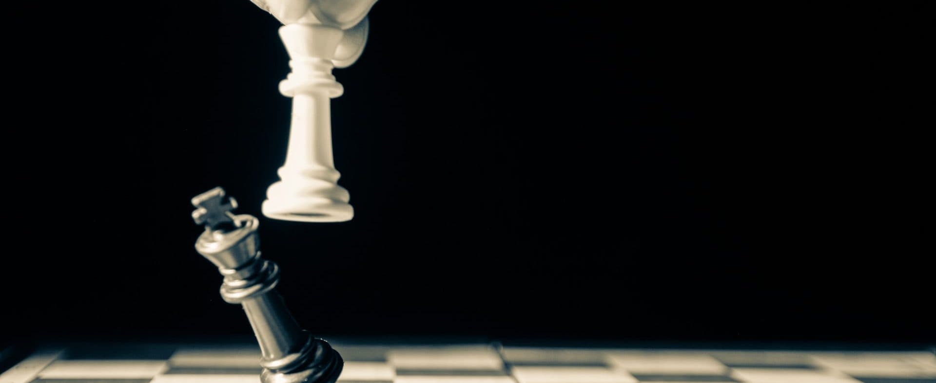 White chess king toppling a black chess king