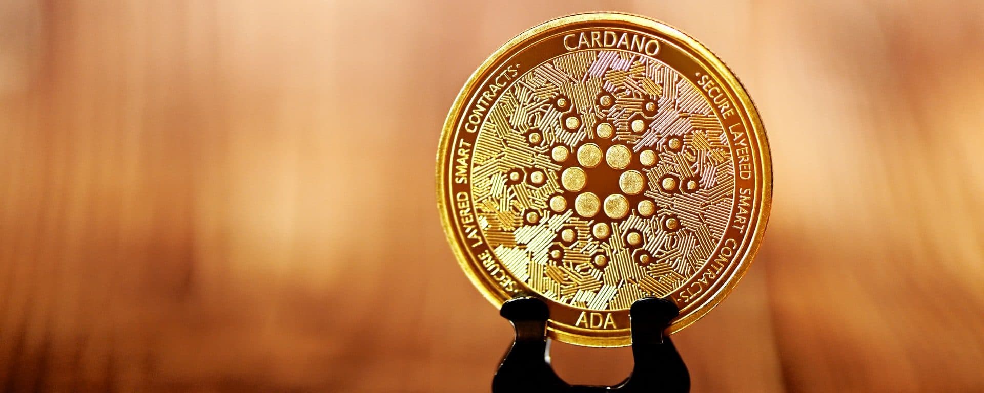 Gold-colored Cardano ADA token displayed on a stand