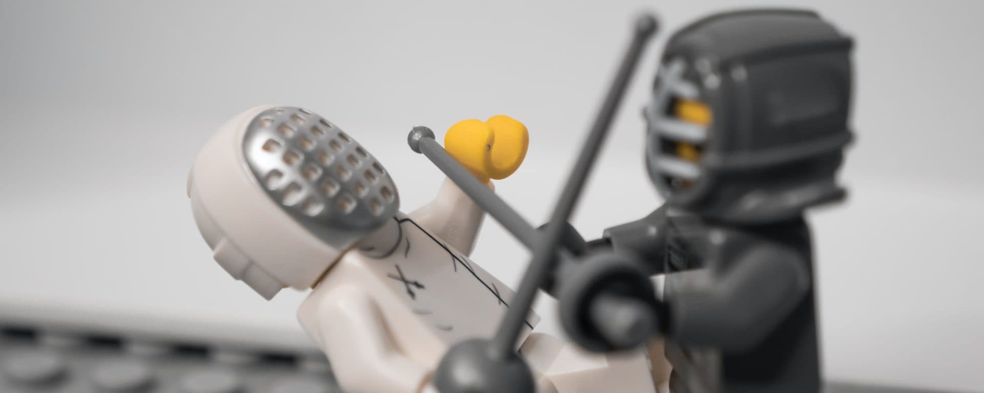 Toy fencer and armored toy figure dueling with swords