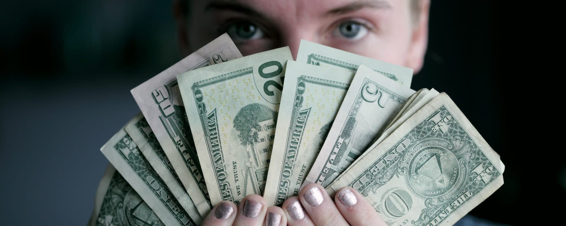 Person holding a fan of U.S. dollar bills