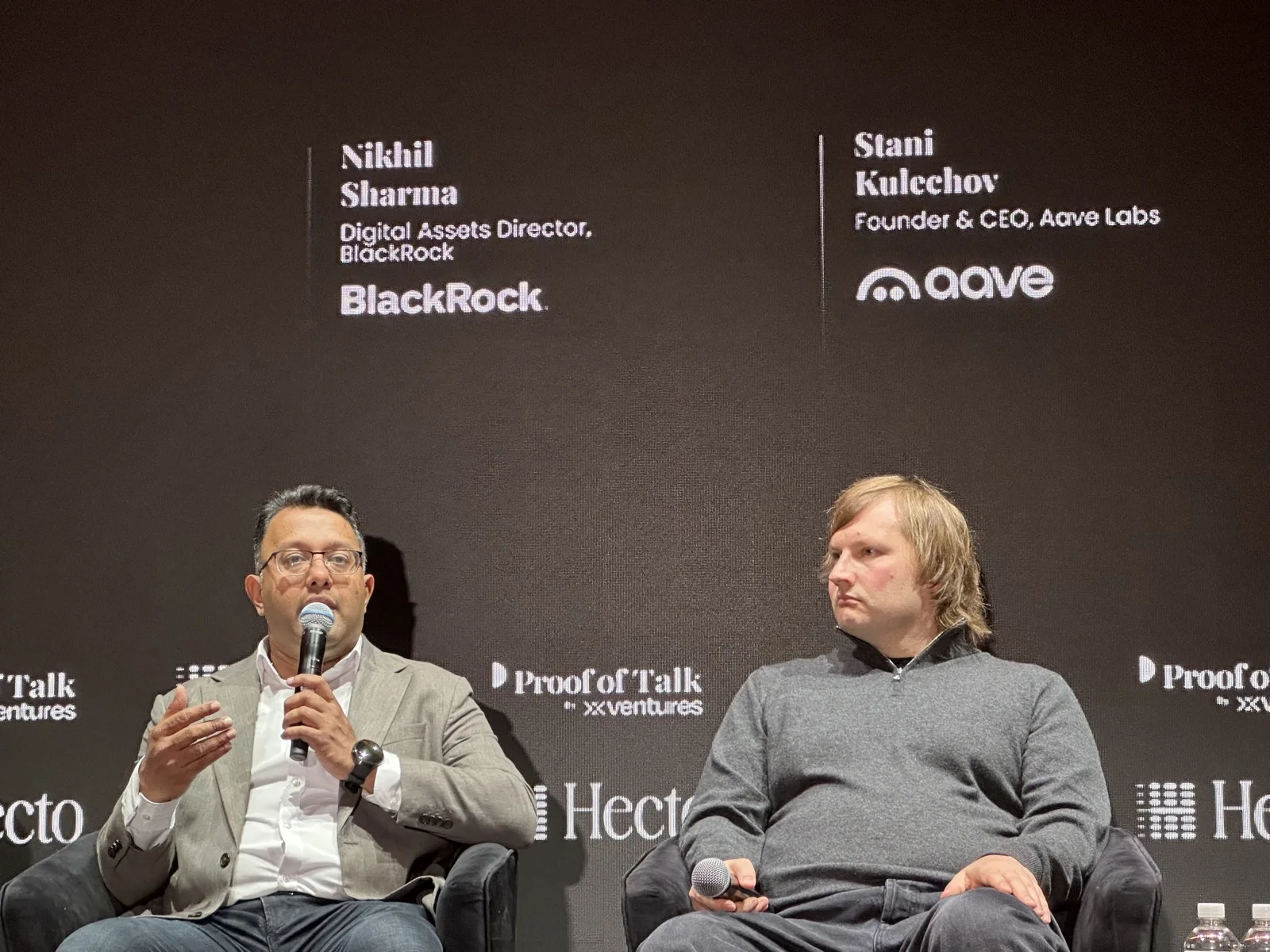 On stage at Proof of Talk: Nikhil Sharma, Digital Assets Director at BlackRock, next to Stani Kulechov, founder and CEO of Aave Labs.